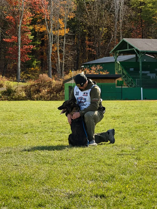 Scott Carlson kneeling with his dog on a competition field