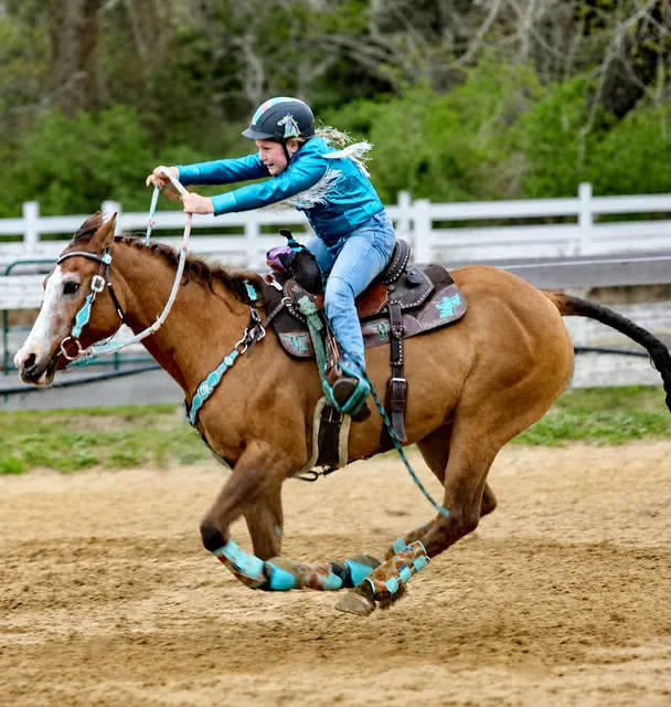A young rider barrel racing on a chestnut horse